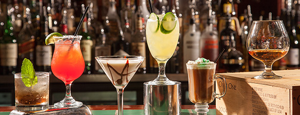 Various mixed drinks in a row on a bar